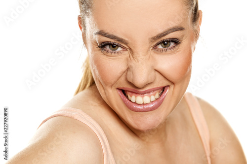 frowned and happy woman shows her teeth on a white background