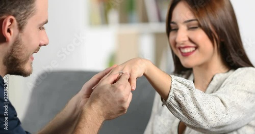 Happy man putting engagement ring in the hand of his girlfriend at home