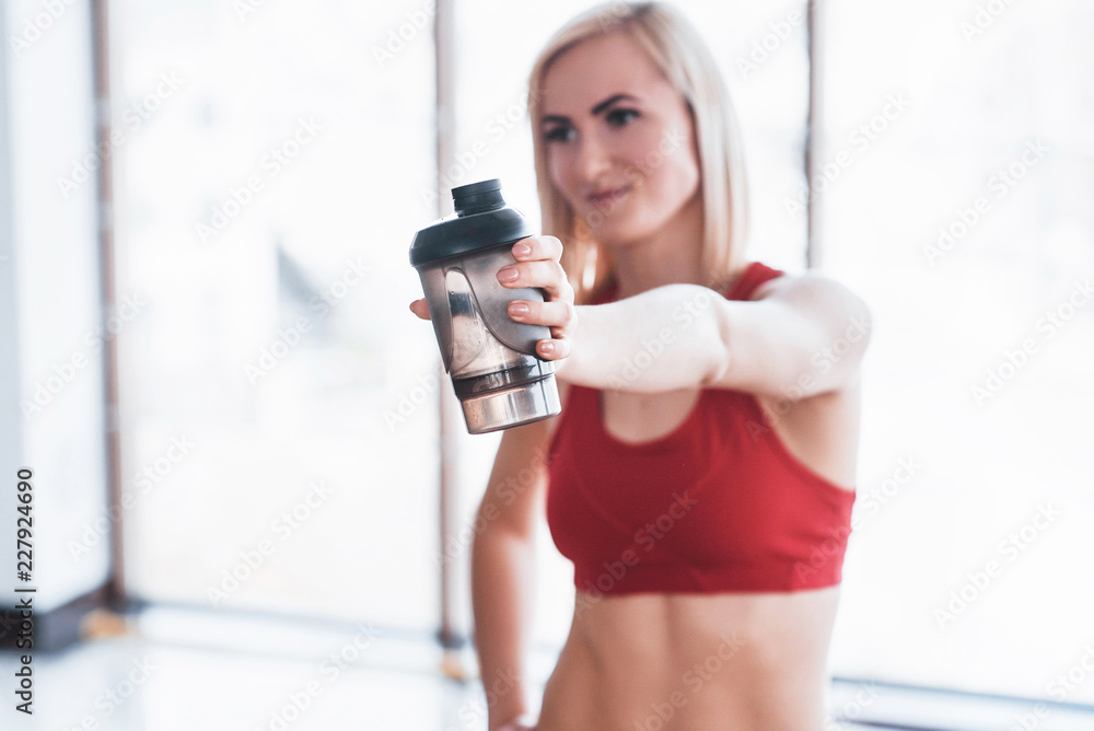 Photo of attractive fitness woman in gym and holding bottle of water Photo of attractive fitness woman in gym and holding bottle of water