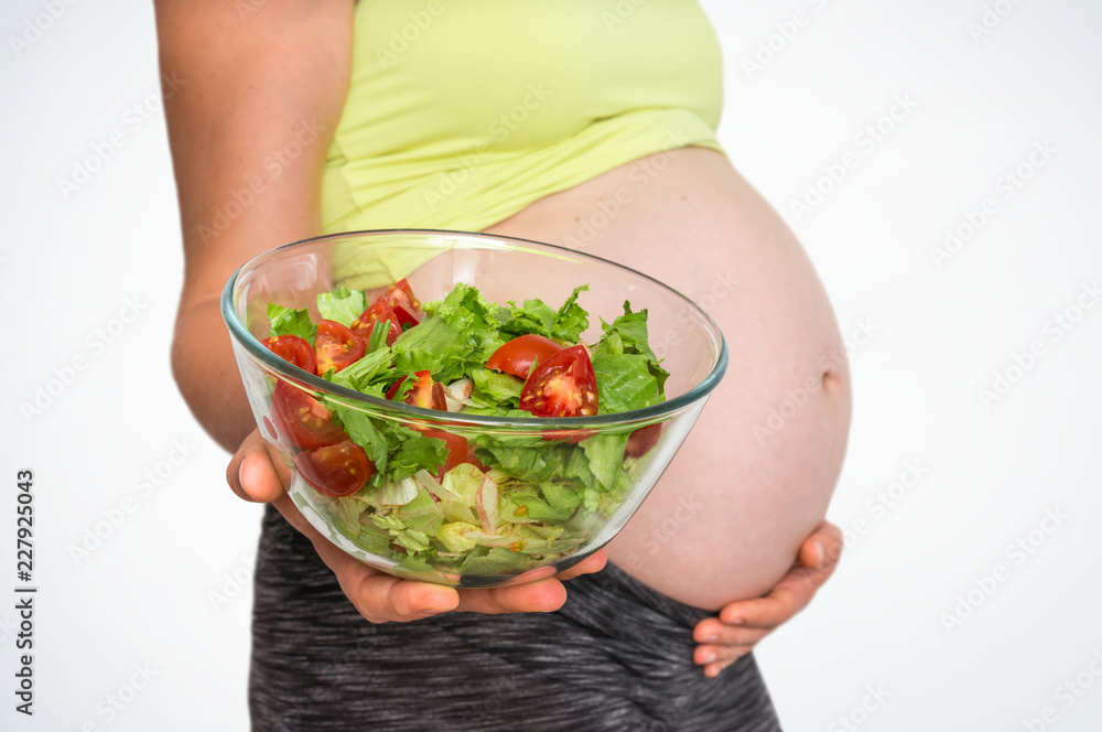 Pregnant woman with vegetables salad isolated on white Pregnant woman with vegetables salad isolated on white