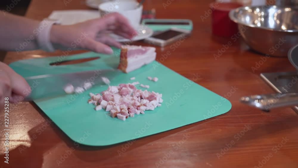 female hands chopping bacon on turquoise chopping board female hands chopping bacon on turquoise chopping board