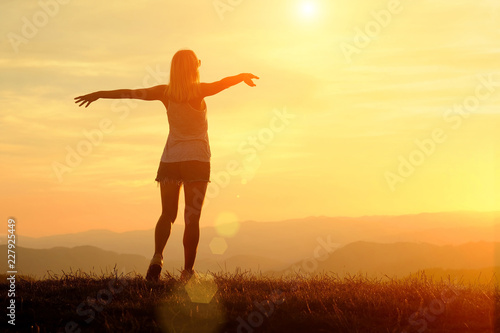 Happy woman with open arms stay on the peak of the mountain 