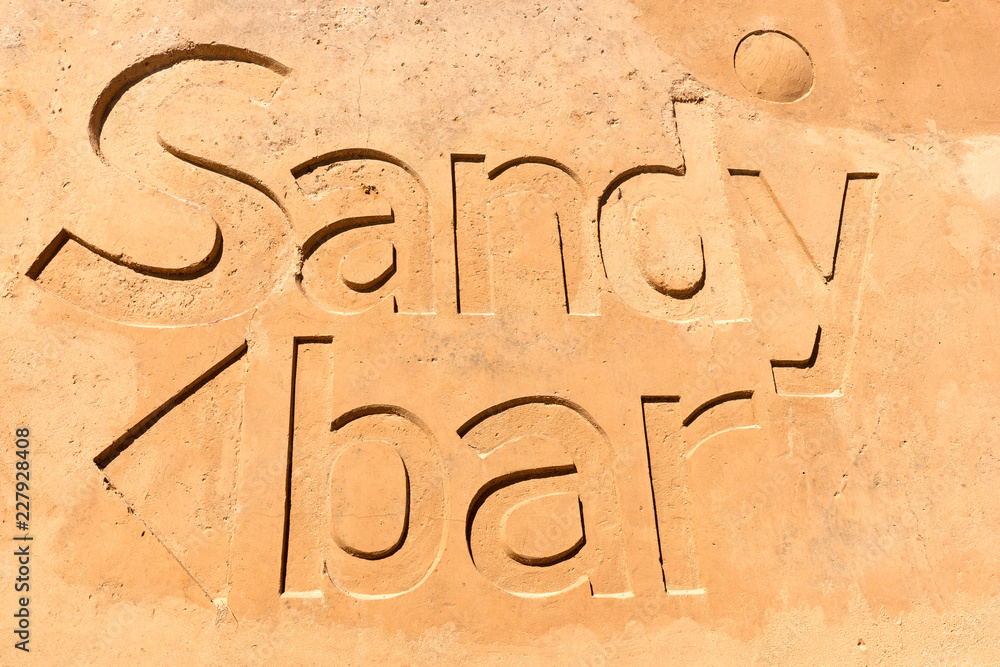 Sandy bar written in the sand on the beach