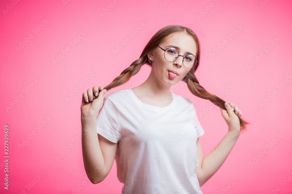 Funny cute young girl showing tongue looking at camera over pink background. Funny cute young girl showing tongue looking at camera over pink background.