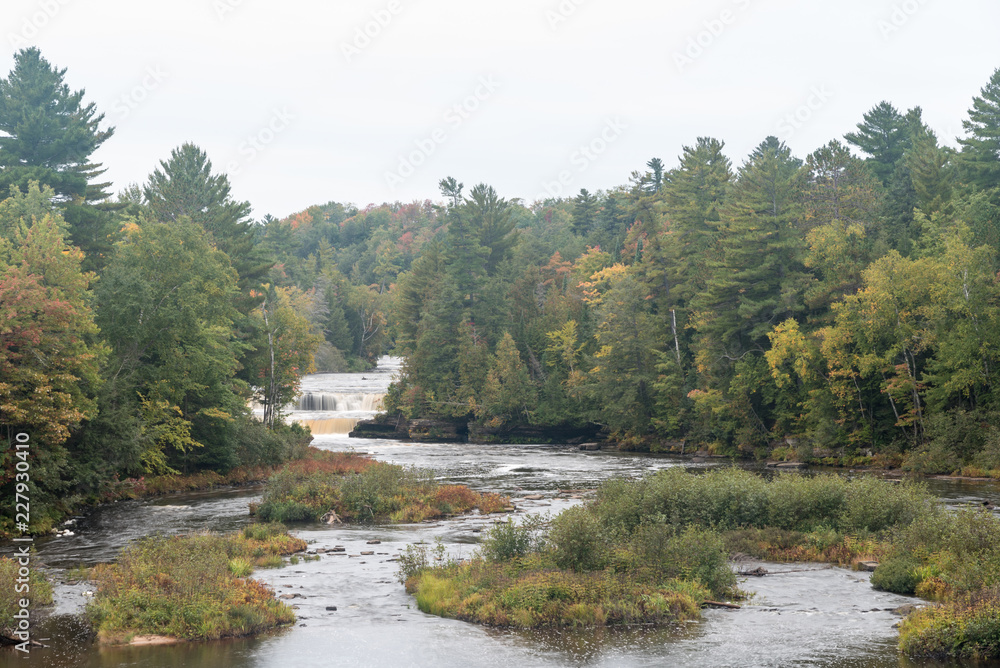 Tannin stained rushing water of Tahquamenon River rushing over the sandstone falls in early autumn as the foliage is just starting to change in the Upper Peninsula, Michigan Tannin stained rushing water of Tahquamenon River rushing over the sandstone falls in early autumn as the foliage is just starting to change in the Upper Peninsula, Michigan
