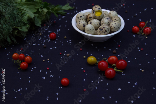 dill, parsley, sorrel and quail eggs in a white plate with tomatoes and sea salt and pepper mixture in a dark background