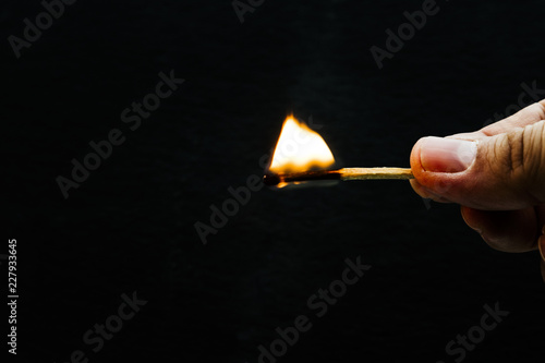 hand holding lighted match with black background