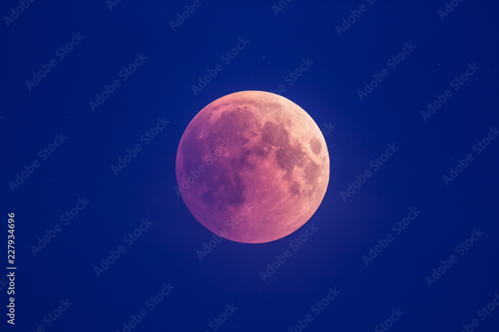 Super Bloody Moon, beginning of full eclipse phase against blue starry sky background Super Bloody Moon, beginning of full eclipse phase against blue starry sky background