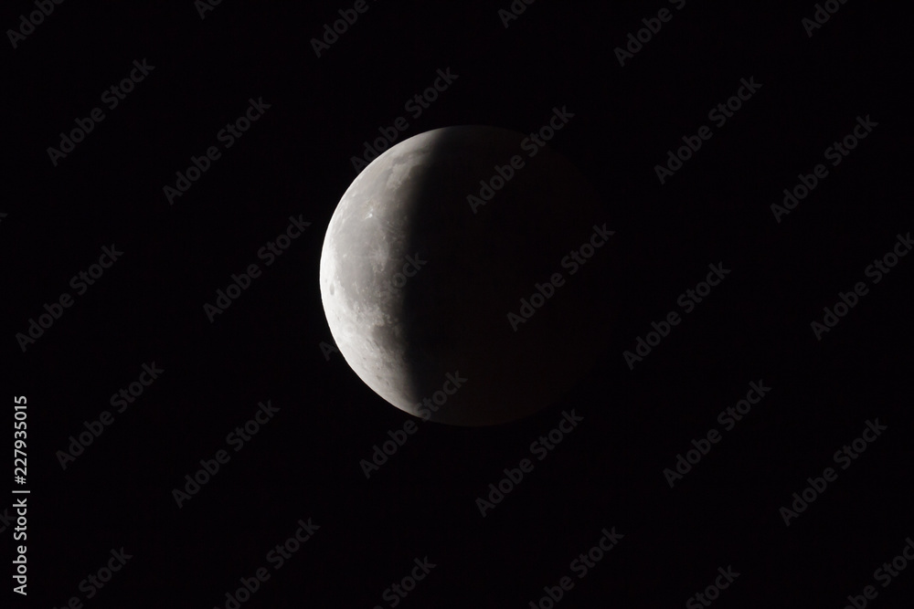 Super Bloody Moon, full eclipse end phase against black sky background, three-quarters of the Moon surface covered by Earth's shadow