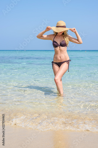 Woman at the beach in Cyprus vertical. Hat and swimsuite. Beautiful Summer se...