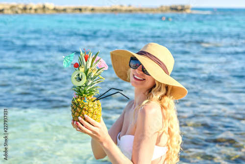 Pineapple cocktail at the beach. Happy girl drinking fresh juicy cocktails. A...