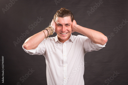 Handsome man covering his ears with both hands and looking at the camera on brown background.