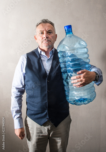 uomo che regge enorme bottiglia di acqua in mano