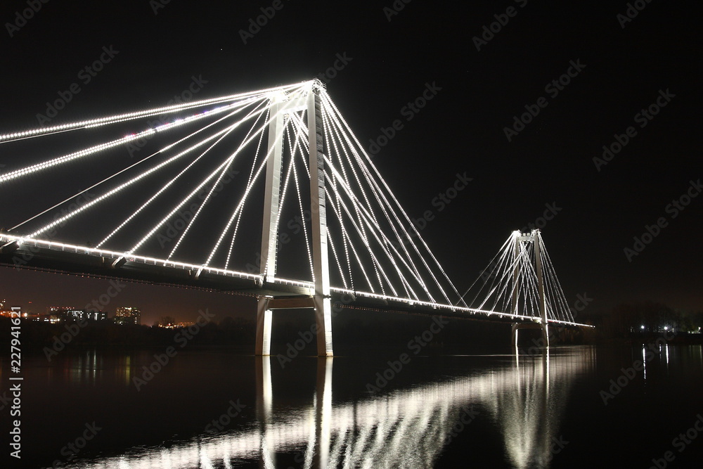 Obraz premium Night illumination on the cable-stayed bridge over the river.