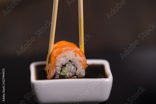 Person dipping a fresh sushi roll in soy sauce