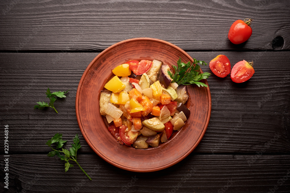 Spicy vegetable stew on a brown plate and a wooden table. Mixed vegetable stew Spicy vegetable stew on a brown plate and a wooden table. Mixed vegetable stew