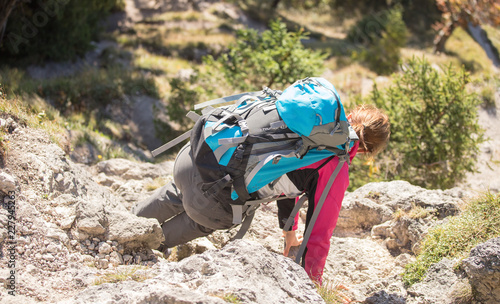 Junge Frau mit Wanderrucksack klettert den Fels hinab