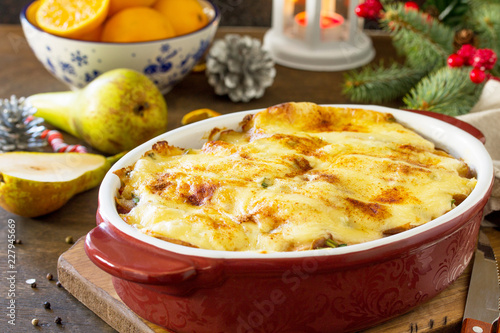 Potato gratin with pear, raclette cheese, and bacon on a festive Christmas table.Traditional french cuisine.