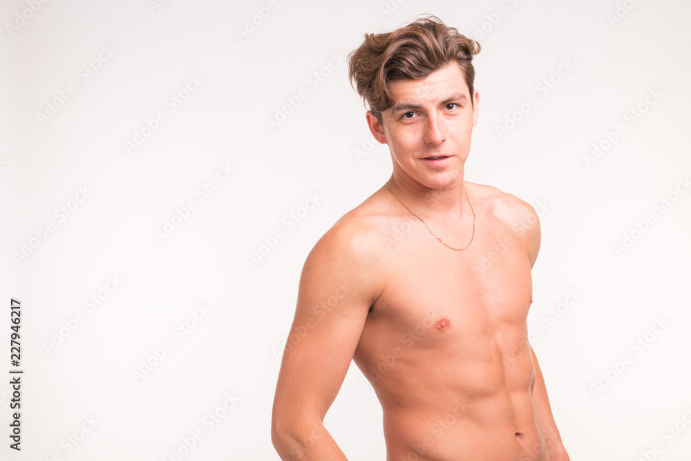 Fototapeta premium People, gesture and sport concept - young confident shirtless man showing fists on white background with copy space