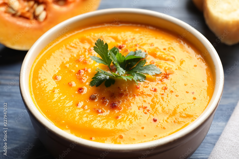 Delicious pumpkin cream soup with parsley and spices in bowl on table, closeup Delicious pumpkin cream soup with parsley and spices in bowl on table, closeup
