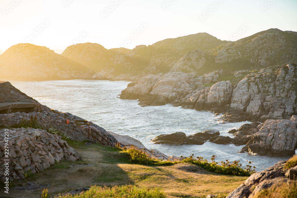 Serene scandinavian summer landscape on south coast of Norway. Rocky Mountains, fjord from top. Sunset sky. Lindesnes