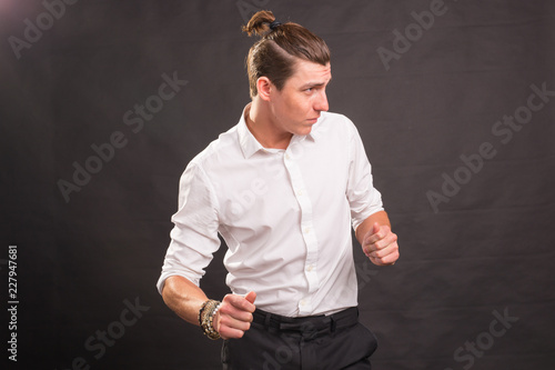 People, fun and style concept - handsome man with with funny haircut dancing on brown background