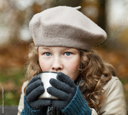 Fotografie Girl in winter cloths drinking from flask cup