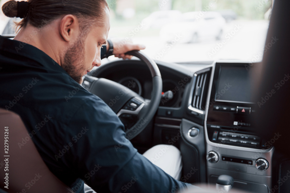 Confident young businessman sitting at the wheel of his new car Confident young businessman sitting at the wheel of his new car