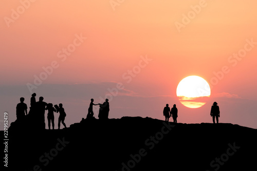 silhouette of people relax on the mountains with sunset in the evening.