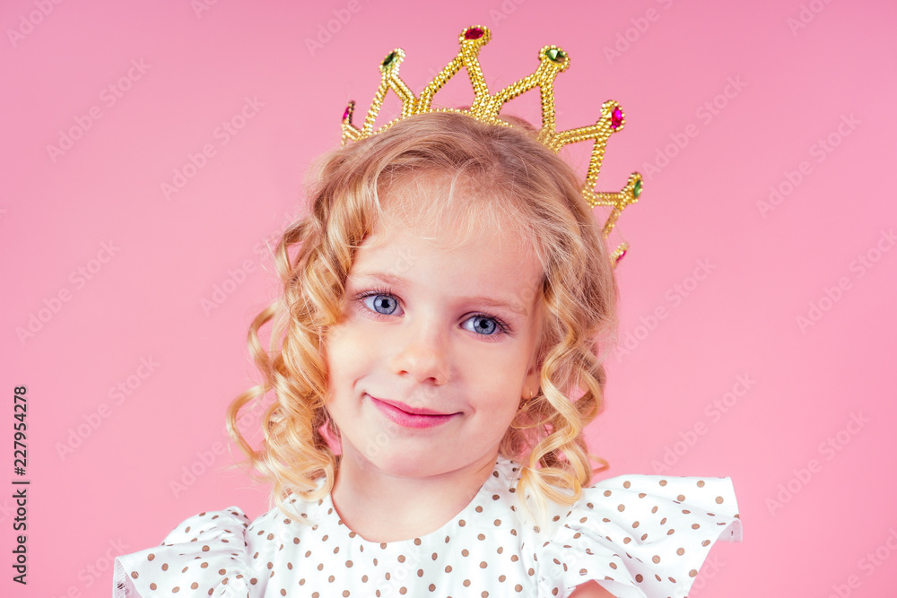 little girl beauty queen blue eyes, curls blonde hairstyle with a tiara crown on her head in a cute white dress in peas posing in the studio on a pink background.birthday celebration,Beauty contest little girl beauty queen blue eyes, curls blonde hairstyle with a tiara crown on her head in a cute white dress in peas posing in the studio on a pink background.birthday celebration,Beauty contest