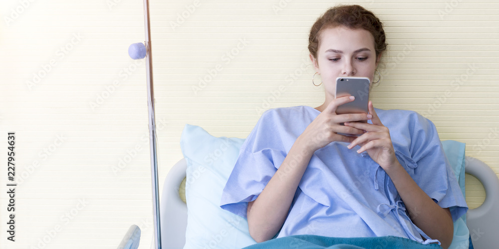 Attractive young woman patient working and typing information on mobile phone in hospital bed. Connected world to business project when sick.Copy space. Attractive young woman patient working and typing information on mobile phone in hospital bed. Connected world to business project when sick.Copy space.