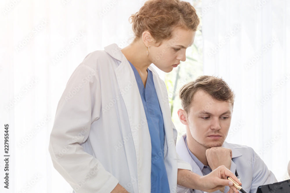 Medical professionals caucasian man holding xray and conversation about patient with young doctor woman.Stressed and worry doctor gives bad news.Close up and copy space. Medical professionals caucasian man holding xray and conversation about patient with young doctor woman.Stressed and worry doctor gives bad news.Close up and copy space.