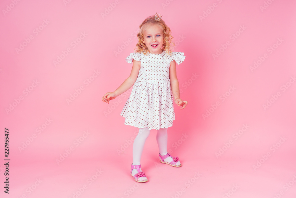Beautiful queen in gold crown.little shopping girl in a princess fashion dress. Pretty child preparing for a birthday Easter party on a pink background in the studio. Beautiful queen in gold crown.little shopping girl in a princess fashion dress. Pretty child preparing for a birthday Easter party on a pink background in the studio.