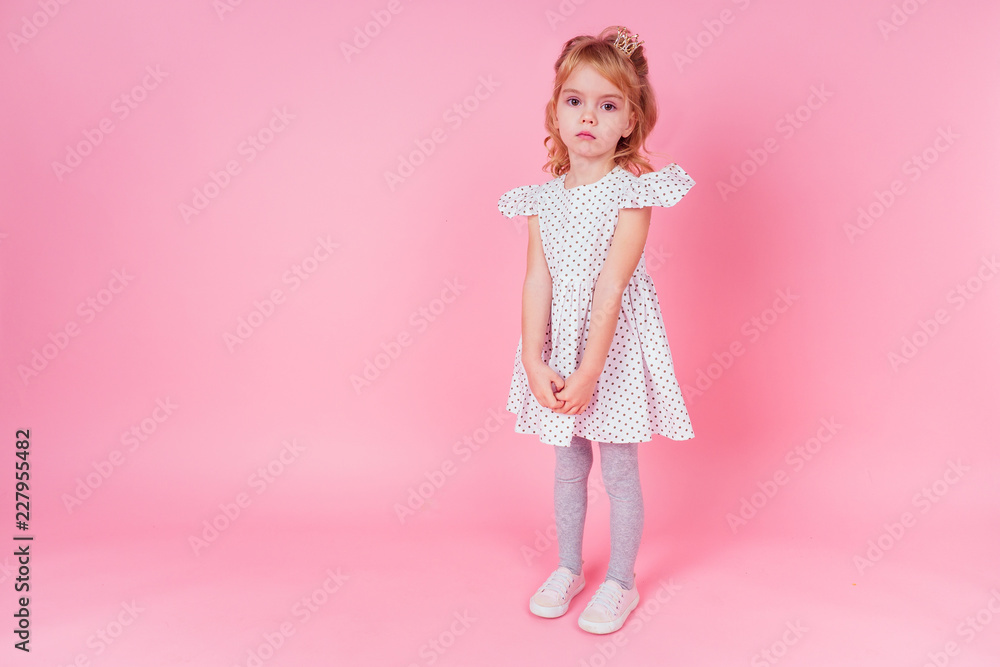 Beautiful queen in gold crown.little shopping girl in a princess fashion dress. Pretty child preparing for a birthday Easter party on a pink background in the studio.dancer ballerina