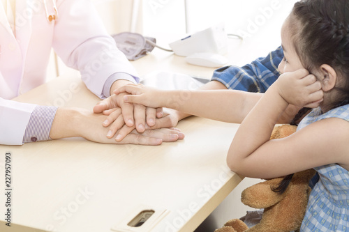 Pediatrician (doctor) man giving fist bump (High Five To),reassuring and discussing kid at surgery.Mother Caucasian and kid smiling in hospital room.Copy space.