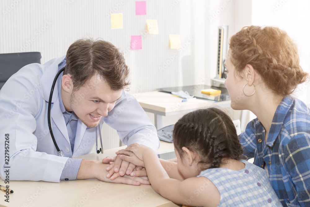 Pediatrician (doctor) man giving fist bump (High Five To),reassuring and discussing kid at surgery.Mother Caucasian and kid smiling in hospital room.Copy space. Pediatrician (doctor) man giving fist bump (High Five To),reassuring and discussing kid at surgery.Mother Caucasian and kid smiling in hospital room.Copy space.