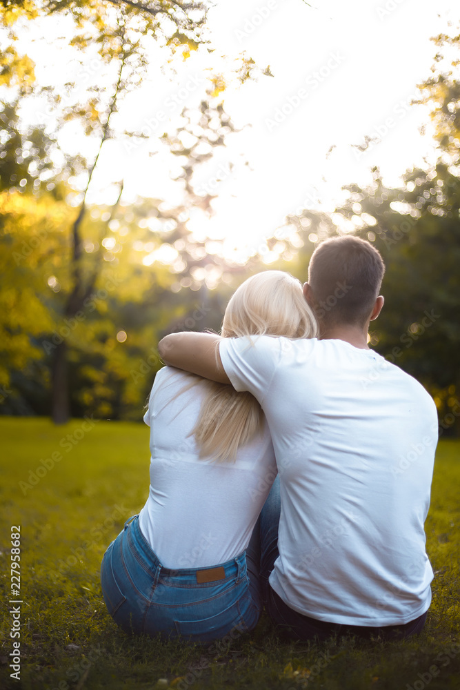 Loving couple sitting in nature green park on grass hugging with beautiful sundown light. Loving couple sitting in nature green park on grass hugging with beautiful sundown light.
