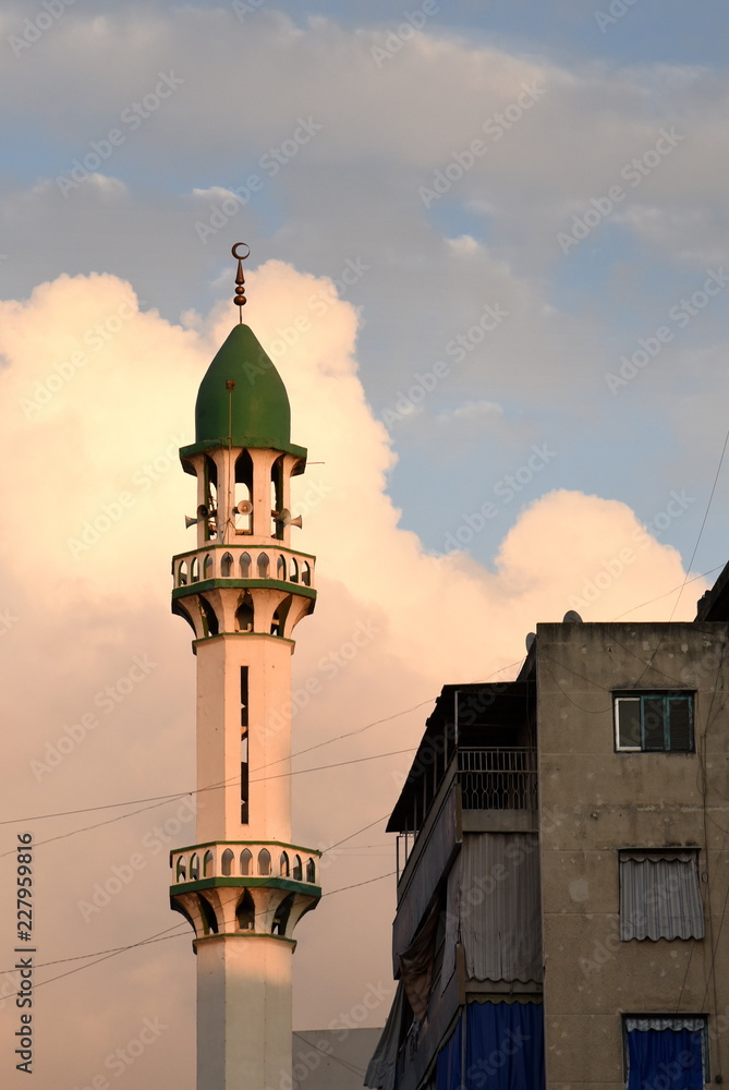 Schlankes Minarett vor malerischer Wolke in Beirut und marodes Wohnhaus im Vordergrund