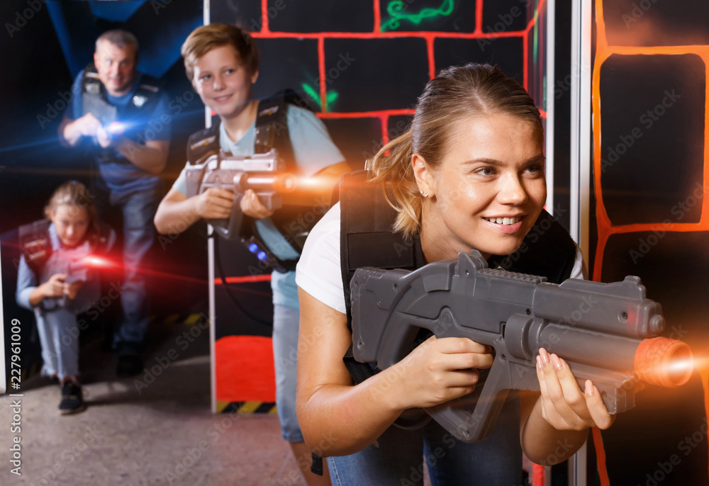 Happy young girl with laser gun  during laser tag game with  pla - obrazy, fototapety, plakaty 