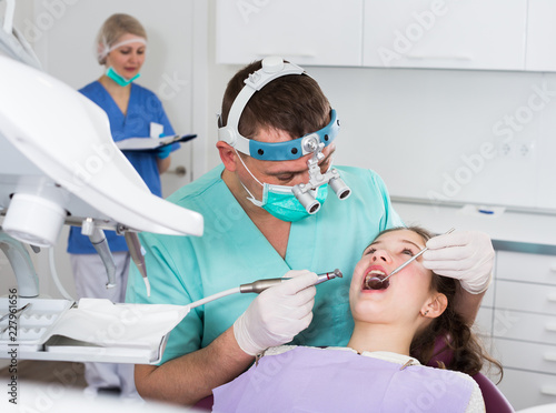 Confident male dentist treating girl