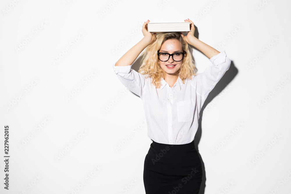 Young blonde business woman holds the book on a head is isolated on a white background. Young blonde business woman holds the book on a head is isolated on a white background.