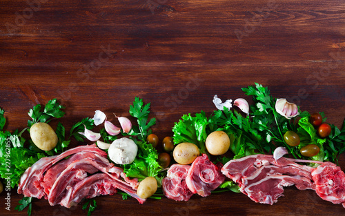 Raw mutton and vegetables assortment on natural wooden background