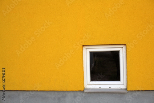 Yellow wall with white window on the corner; building and architecture concept.