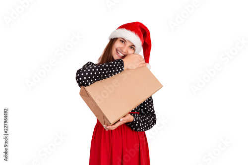 Happy woman in chistmas hat hugs a gift wrapped in recycled paper. isolated on white background. holidays concept