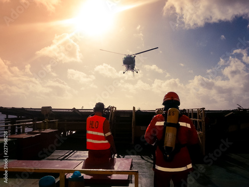 Helicopter landing officer (HLO) and member of a fire team receiving landing helicopter on a offshore drilling rig photo