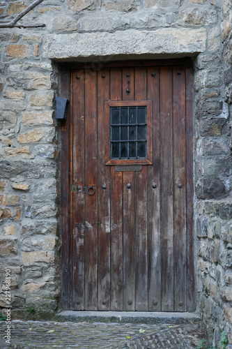 Ancient dark wood entrance door of a stone house © jujopeto
