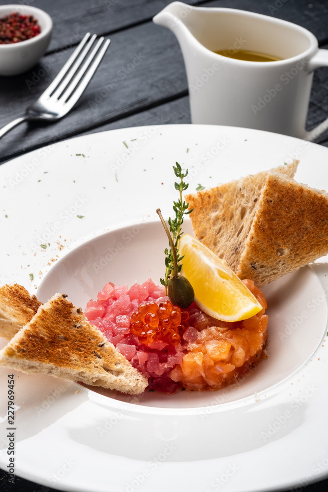 Tartar of salmon and tuna with capers, lemon and red caviar. Tartar of salmon and tuna with capers, lemon and red caviar.