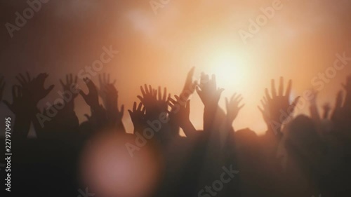 Silhouettes of hands raised in worship with sunlight. photo