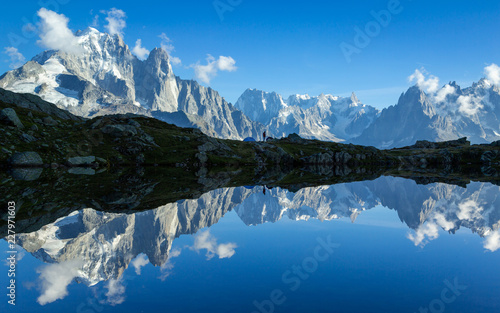 Hiker at his tent in the Mont Blanc massif reflected in Lac de Chesery. Chamonix  France.