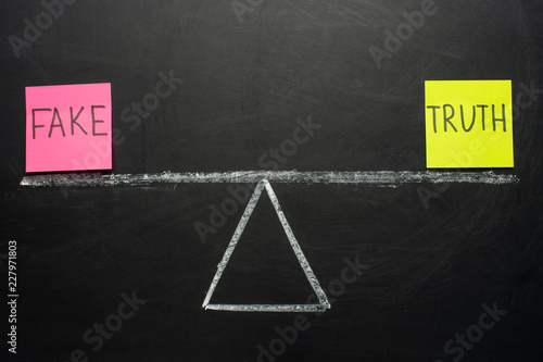 Scales with truth and fake. The concept on the blackboard.